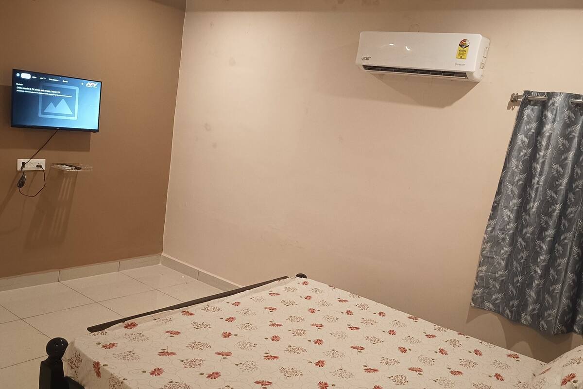 Quarto com cama, ar-condicionado, televisão e cortina.