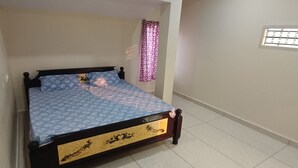 A bedroom with a bed, an air conditioner, a ceiling fan, a window with a curtain, and a small window on the wall. - Hotel Homestay Bhimavaram (Bhimavaram)