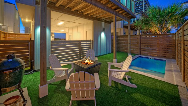 An outdoor patio with a pool, a grill, and Adirondack chairs. - Steps to Beach • Pool + Fire Pit + Golf Cart Boardwalk Access | Southern Cross (Port Aransas)