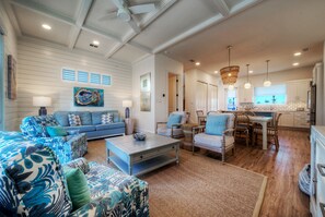 A spacious living room with a sofa, chairs, a coffee table, and a dining area with a table and chairs. - Steps to Beach • Pool + Fire Pit + Golf Cart Boardwalk Access | Southern Cross (Port Aransas)