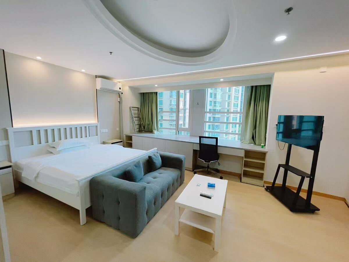 A modern hotel room with a large bed, a sofa, a desk, and a TV.