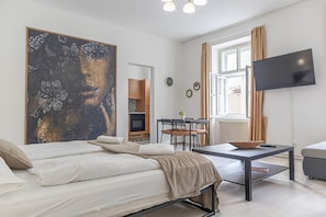 Ein modernes Hotelzimmer mit einem Bett, einem Esstisch, einem Fernseher und einem großen Gemälde.
