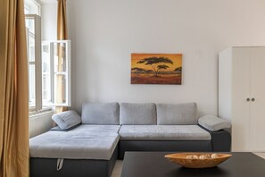 Ein modernes Wohnzimmer mit einer grauen Eckcouch, einem schwarzen Couchtisch und einem Gemälde einer Savannenlandschaft.