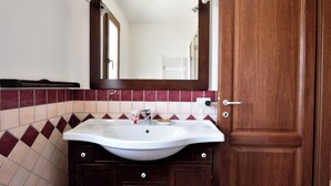 Een badkamer met een witte wastafel, een houten kastje en een spiegel erboven.