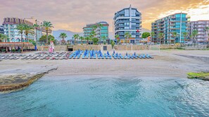A beachside hotel with multiple floors, a pool area with sun loungers, and a view of the sea. - GRAND BARHAN HOTEL (Alanya)
