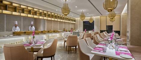 Un restaurant moderne doté de longues tables conviviales, de hauts plafonds et d’éléments d’éclairage décoratifs.
