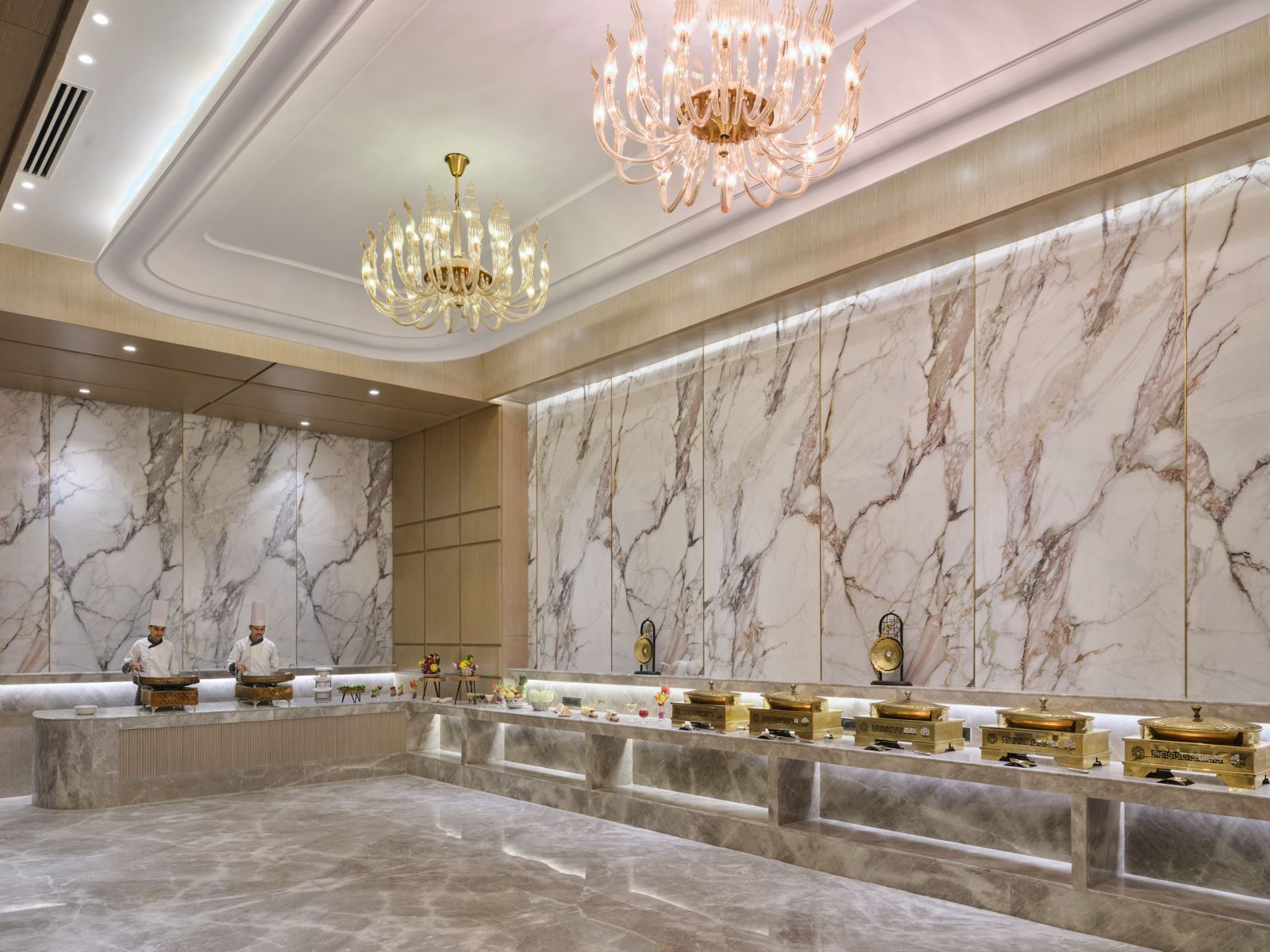 A luxurious lobby with marble walls, a central reception desk, and a chandelier.