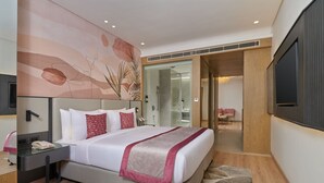 Une chambre d’hôtel moderne avec un grand lit, une table de chevet avec un téléphone, un miroir et un téléviseur fixé au mur.