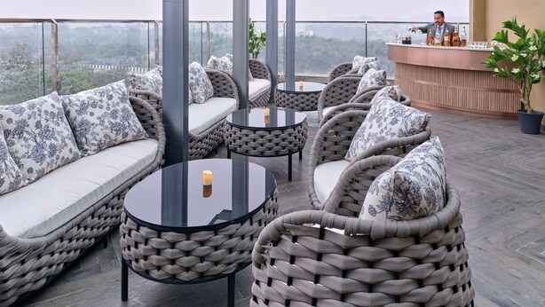 Une terrasse sur le toit, aménagée avec des meubles en osier, un espace bar et une vue sur la ville.