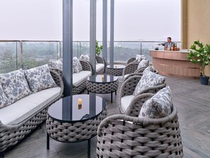 A rooftop terrace with wicker furniture, a bar area, and a view of the city. - Regenta Ranjit Avenue Amritsar (Amritsar)