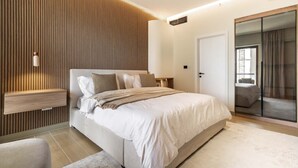 Ein modernes Schlafzimmer mit einem großen Bett, einem Nachttisch, einem Kleiderschrank und einer Glastür zum Balkon.