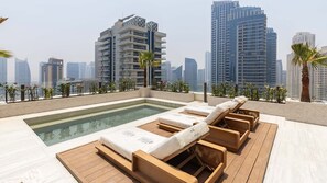 A rooftop pool area with lounge chairs and a view of high-rise buildings. - Ultimate Luxury Penthouse w Pool Marina Views (Dubai)
