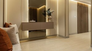 Ein modernes Hotelzimmer mit integriertem Schminktisch, einem Spiegel und einem hölzernen Kleiderschrank.