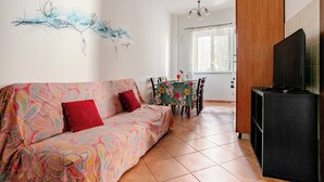 Uma sala de estar com sofá, mesa de jantar e rack para televisão.