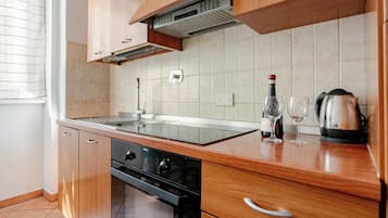 A modern kitchen with wooden cabinets, a built-in oven, and a stainless steel sink.