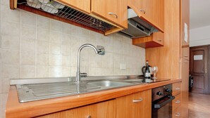 Cozinha com pia de aço inoxidável, armários de madeira e forno embutido.