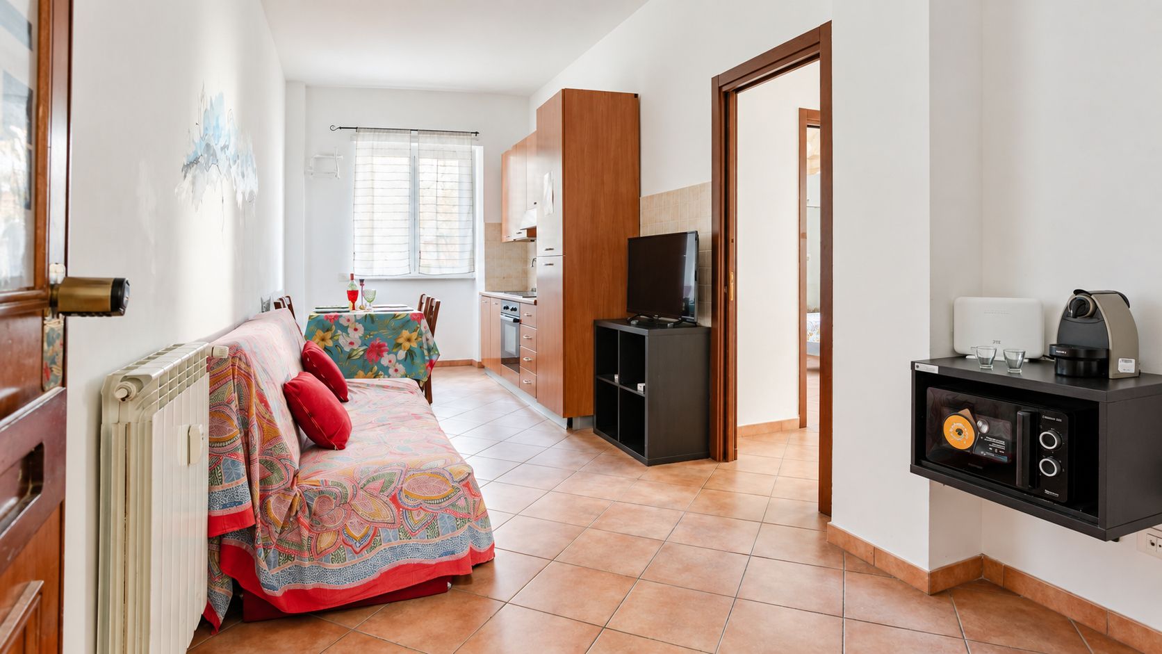 A cozy room with a bed, a small kitchenette, and a television.
