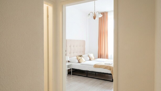 Une chambre à coucher avec un lit, une table de chevet et un luminaire suspendu.