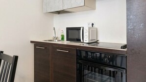 Une cuisine équipée d’un four à micro-ondes, d’un grille-pain, d’un évier et d’un lave-vaisselle.
