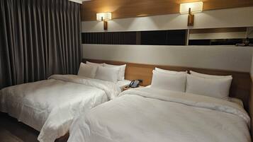 Een hotelkamer met twee bedden, een telefoon en twee wandlampen.