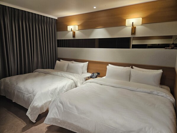 Una habitación de hotel con dos camas, un teléfono y dos lámparas de pared.