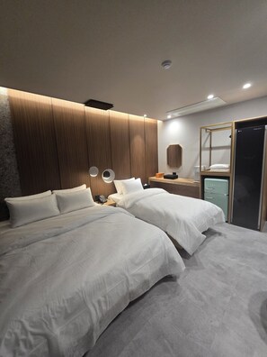 A modern hotel room with two beds, a wooden headboard, a small desk with a lamp, a mirror, and a minibar. - Hound Hotel Tongyeong Jukrim (Tongyeong)