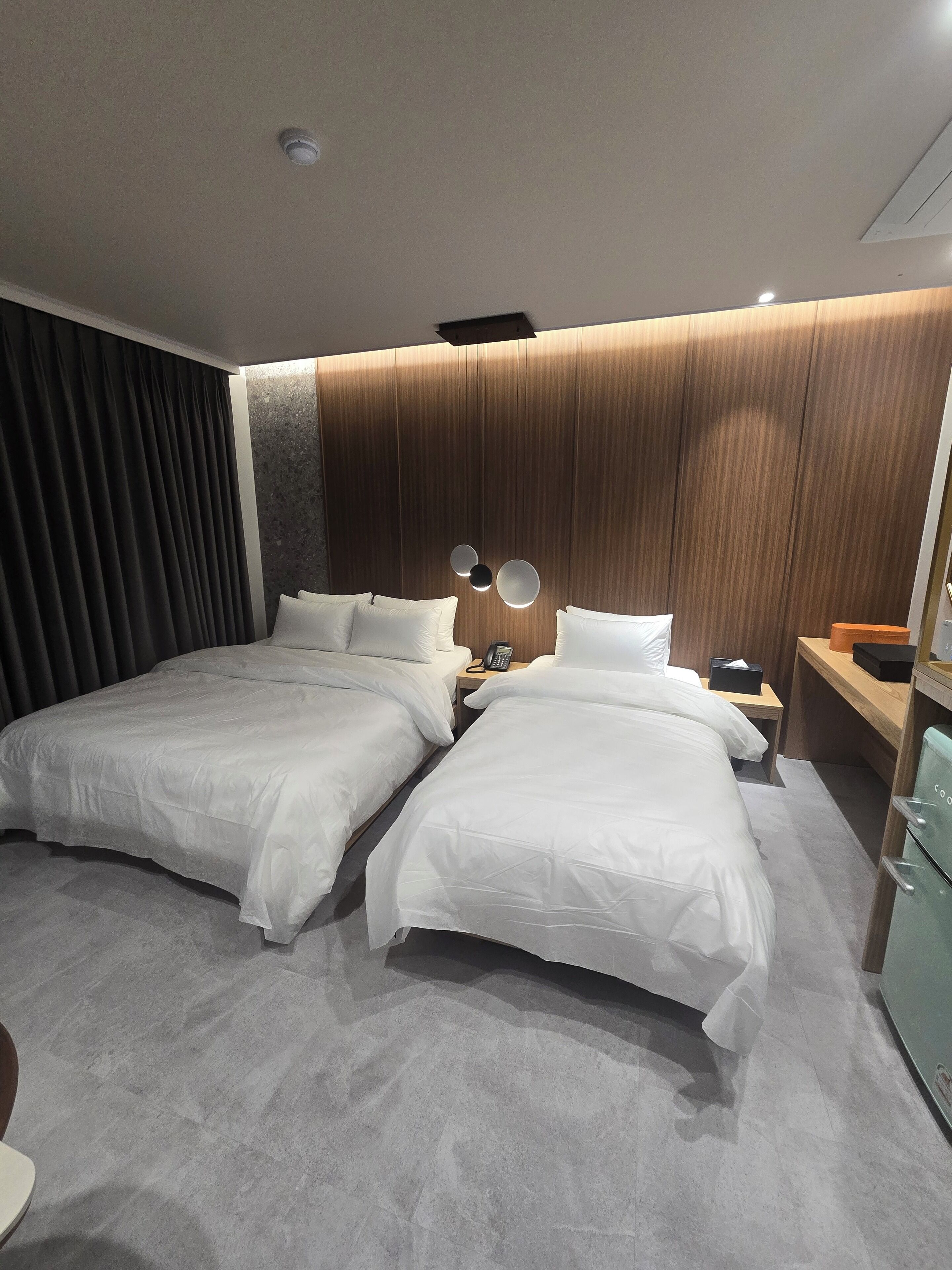 A hotel room with two beds, a wooden headboard, a telephone, and a minibar.