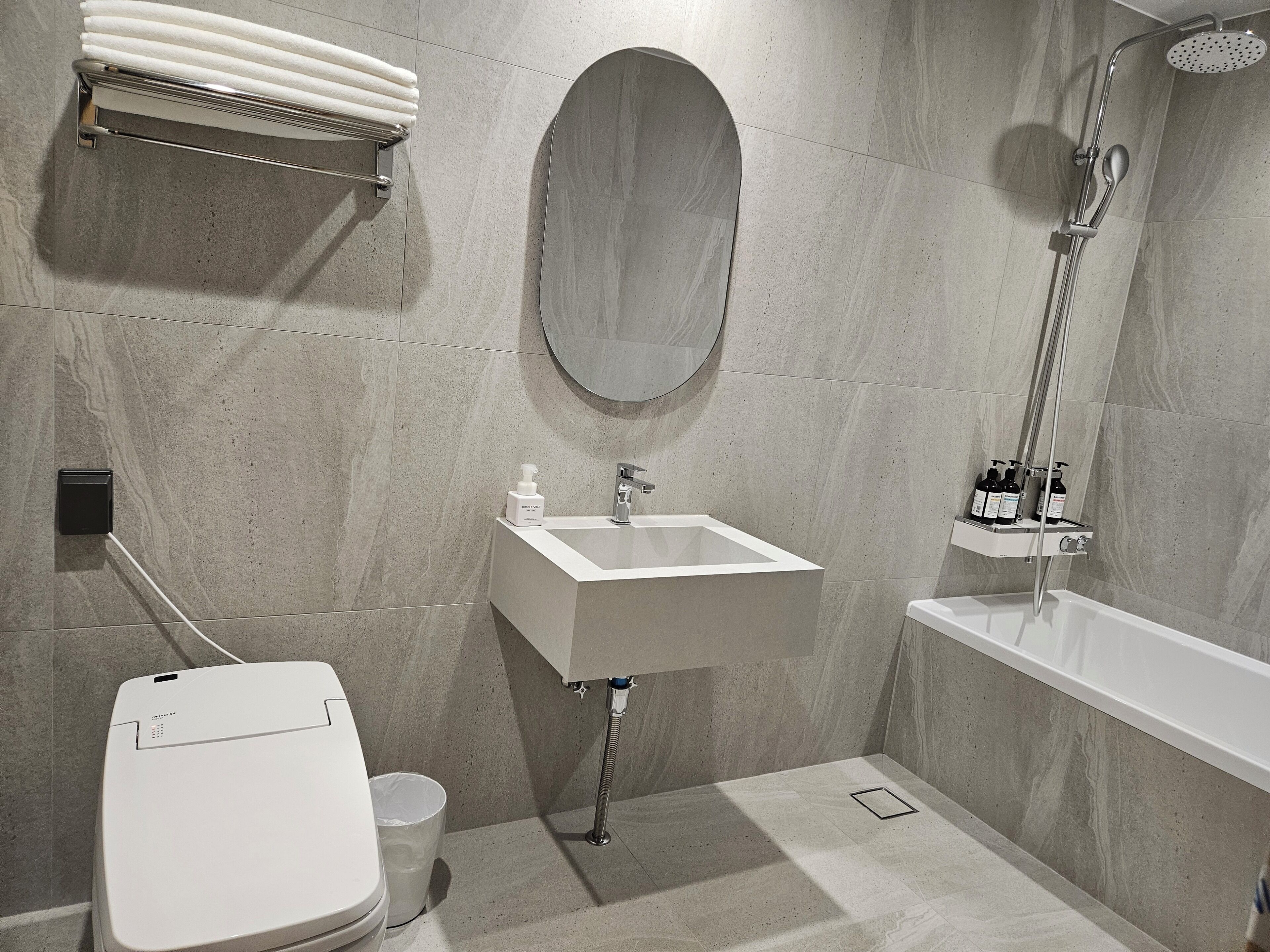 A modern bathroom with a toilet, sink, mirror, and shower.