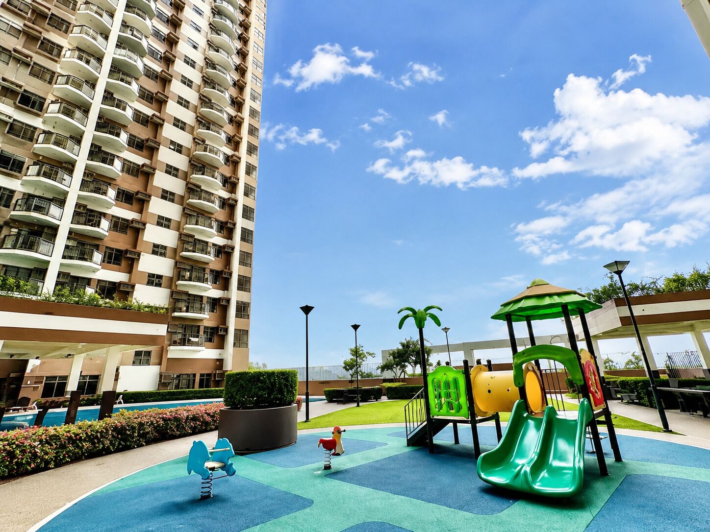 A children's play area with a slide and swings, surrounded by a high-rise building.