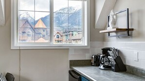 Una cocina con un amplio ventanal, una cafetera y un bloque de cuchillos en la encimera.