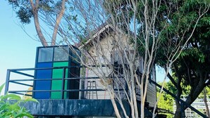 Un edificio rústico con techo inclinado, rodeado de árboles y follaje.