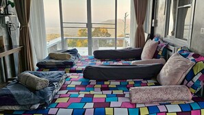 Una habitación con un ventanal grande, una colcha de cama con estampado geométrico colorido y vistas a un paisaje montañoso.