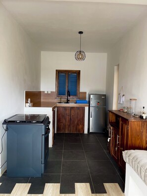 A compact kitchen with a gas stove, a refrigerator, and wooden cabinets.