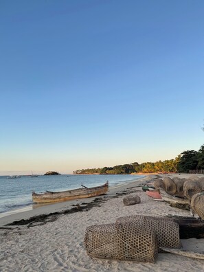 Een strand met boten en vissersnetten op het zand.