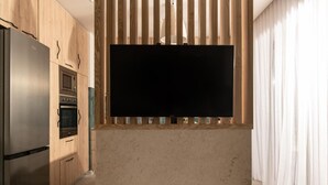 A modern kitchen with a built-in TV, stainless steel appliances, and wooden cabinetry. - Cossoro Cave Villa Vasilikos (Vasilikos)