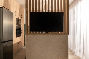A modern kitchen with a built-in TV, stainless steel appliances, and wooden cabinetry. - Cossoro Cave Villa Vasilikos (Vasilikos)