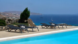 Zona de piscina con sillones de descanso y vistas al mar.
