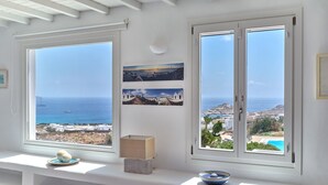 Una habitación con vistas al mar, un banco decorado con objetos y una pared con cuadros enmarcados.