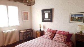 Ein Schlafzimmer mit einem Bett, einem Schreibtisch, einem Stuhl, einem Heizkörper und zwei gerahmten Bildern an der Wand.
