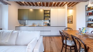 Een moderne keuken met witte kasten, een houten eettafel en een gezellige zithoek met een witte bank.