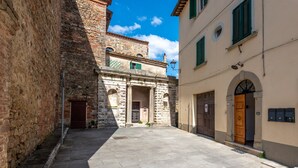 Een smalle straat met stenen gebouwen, een houten deur en een kleine binnenplaats.