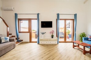 A living room with a sofa, a coffee table, a TV, and a sliding glass door. - Apartment 'Villa Elena' with Sea View, Shared Pool and Air Conditioning (Lu Bagnu)