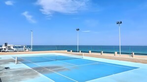 A tennis court with a clear view of the ocean and a beach in the background. - Apartment 'Villa Elena' with Sea View, Shared Pool and Air Conditioning (Lu Bagnu)