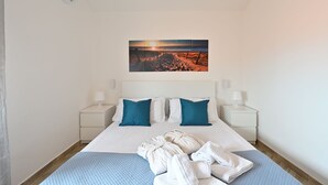 A hotel room with a bed, two nightstands, a wall-mounted air conditioner, and a sunset beach view. - Apartment 'Villa Elena' with Sea View, Shared Pool and Air Conditioning (Lu Bagnu)