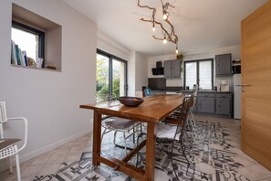A modern kitchen with a wooden table, chairs, and a unique light fixture.