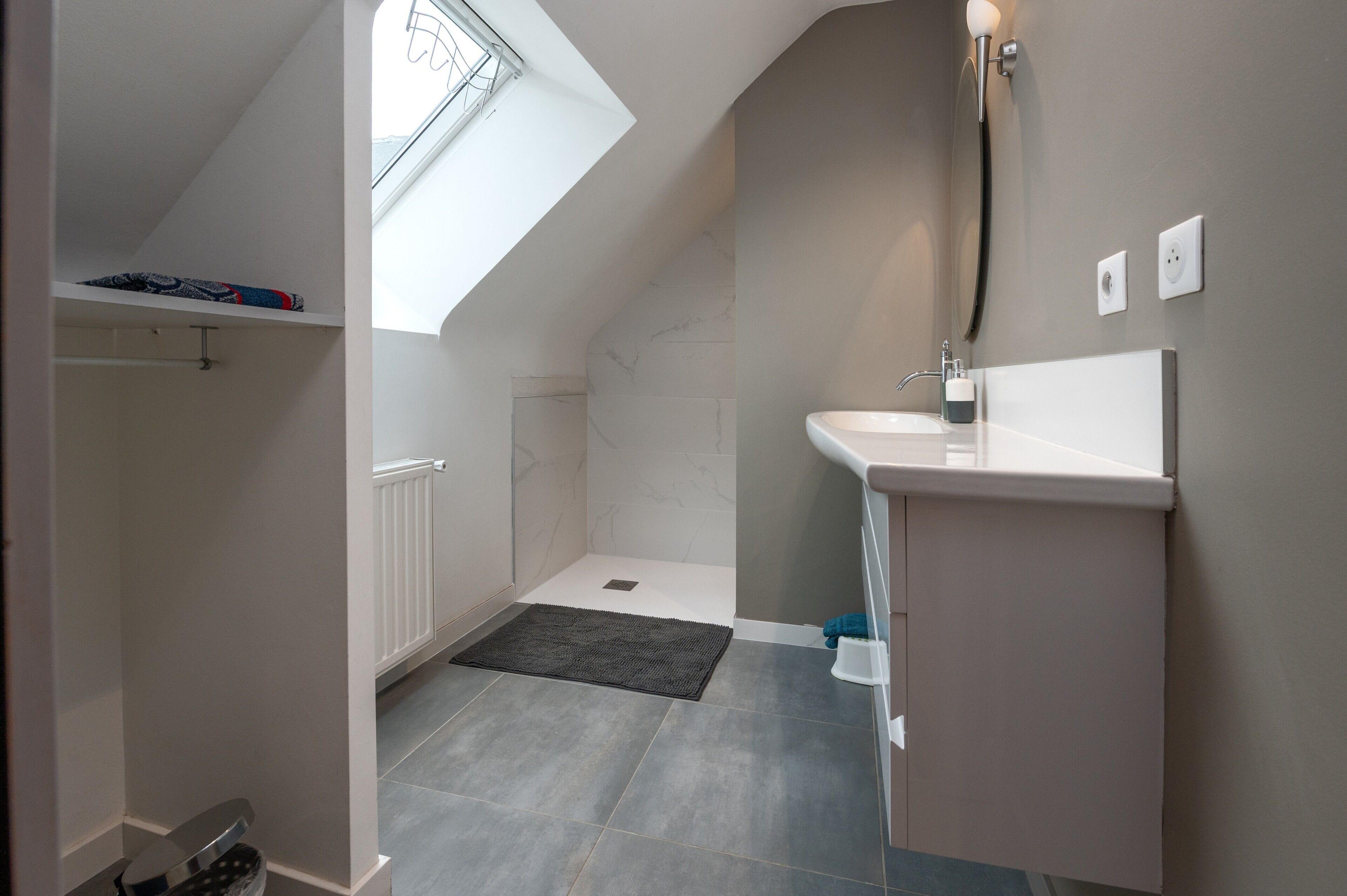 A modern bathroom with a skylight, a shower, and a sink.