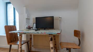 Una stanza piccola con un tavolo, due sedie, una televisione e un termosifone.