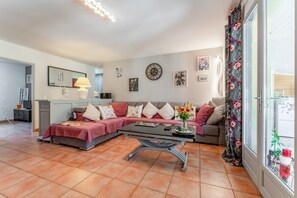 Een woonkamer met een bank, salontafel en een eethoek met een lamp.