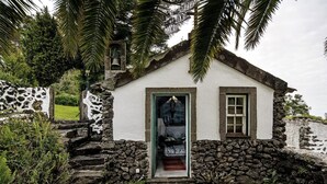 Una casa de piedra con fachada blanca, una puerta de madera y una ventana pequeña.