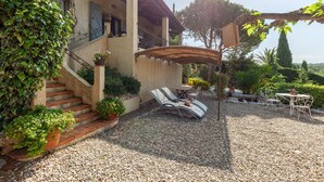 Ein Haus mit überdachter Terrasse, Sitzgelegenheiten im Freien und einem Schotterweg.